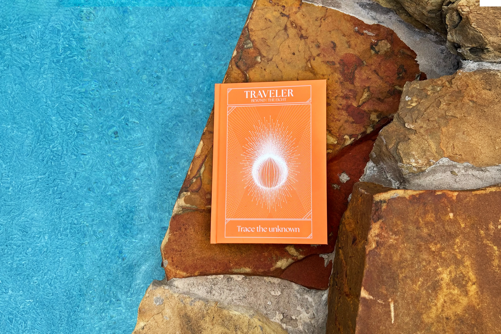 Traveler journal by the Ei8ht placed on natural stone surface with water background, featuring "Trace the unknown".